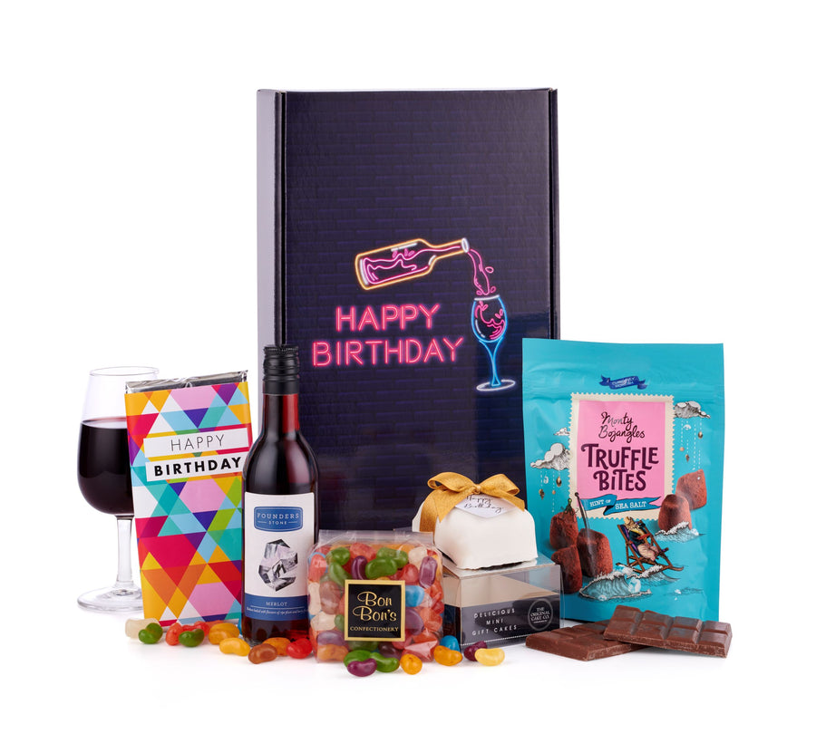 A happy birthday gift box, hand-packed full of sweet treats including jelly beans sweets, a mini birthday cake, truffle bites by Monty Bojangles, milk chocolate with Happy Birthday wrapper placed upon it, not forgetting a personal bottle of Merlot red wine by Founders Stone.